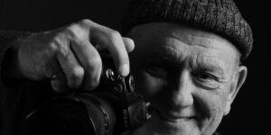 dunkleSchwarz-Weiß-Foto von Rasso Bruckert mit Kamera in der Hand